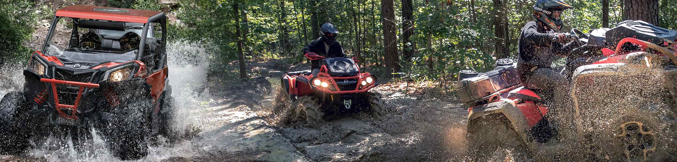 Three people on ATVs navigating a muddy forest trail.