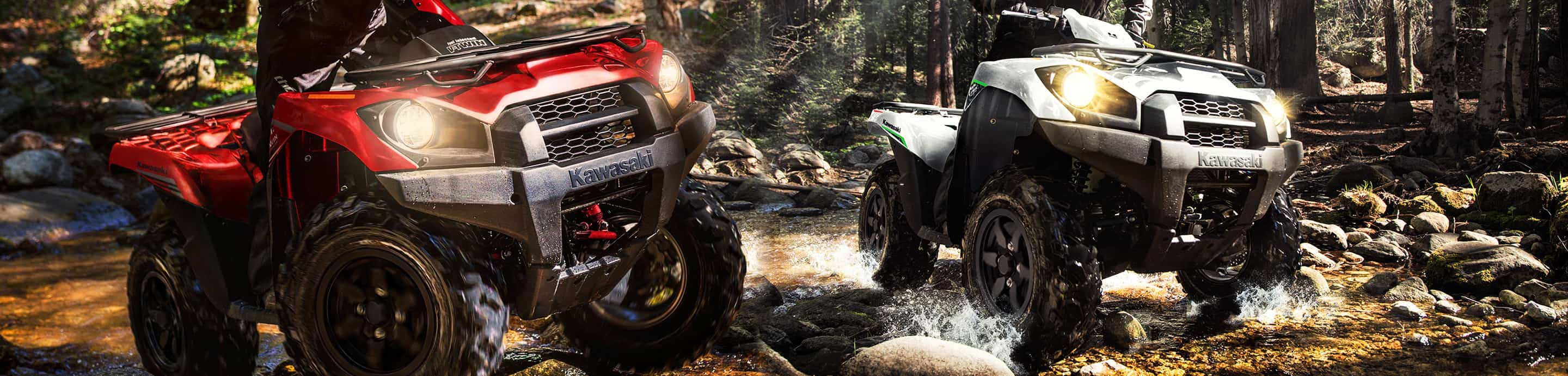 Two off-road vehicles, a red and black ATV and a white and black UTV, navigating through a forest trail.