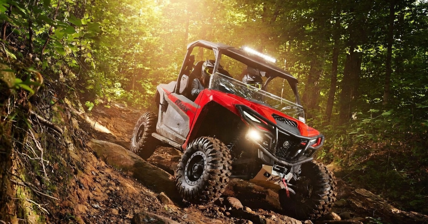 Red off-road vehicle navigating a dirt trail in a forest