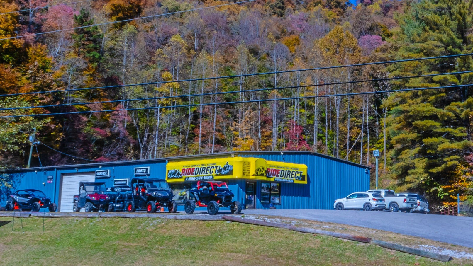 Blue building with a yellow sign in a scenic area with trees and mountains.
