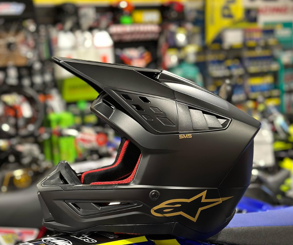 Black motorcycle helmet with a brand logo on a blurred store background